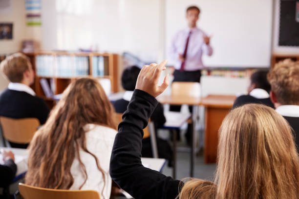 Schulkinder im Klassenzimmer, ein Kind meldet sich